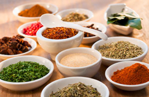 Range of prepared spices and salts in white pots with ladel.