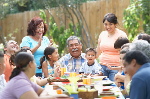 Extended family with many adults and children celebrating around table.